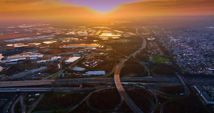 Complicated system of intertwining roads crossing the urban landscape. Busy interchange with hectic traffic at sunset time. Aerial view.