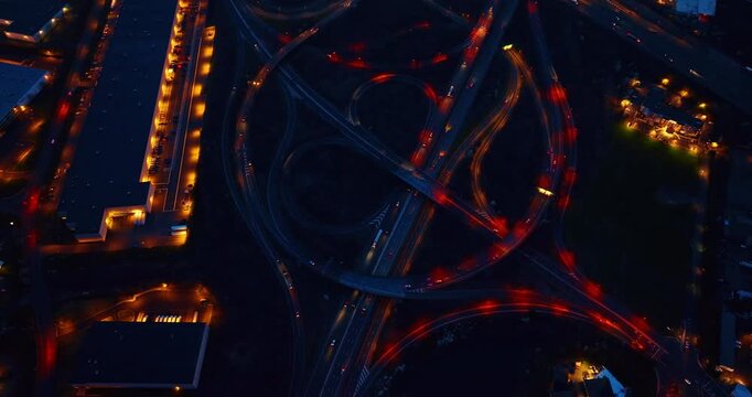Descend over the interchange with red illumination. Modern intersection in the city at night.