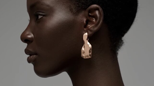 Close up profile of a woman's ear showcasing a unique hammered gold abstract statement earring