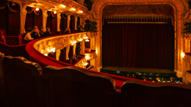 Elegant theatre interior with plush red velvet seats and ornate golden balconies