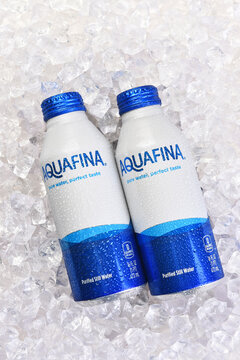 IRVINE, CALIFORNIA - 20 APR 2026: Two aluminum cans of AquaFina purified Still Water on a bed of crushed ice, vertical