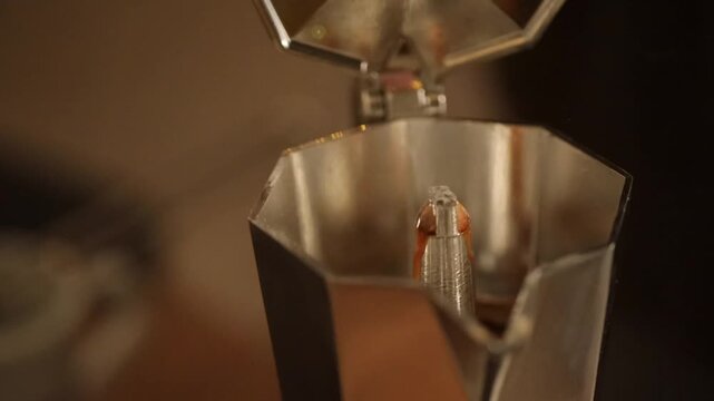 Fresh coffee is poured from a moka pot into a cup in a home kitchen.