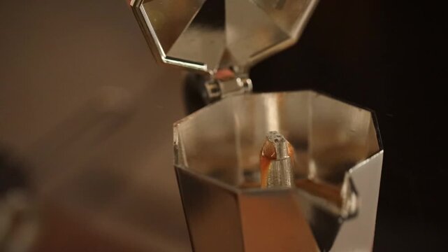 Fresh coffee is poured from a moka pot into a cup in a home kitchen.