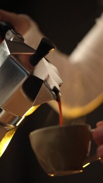 Fresh coffee is poured from a moka pot into a cup in a home kitchen.