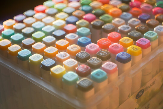 High-angle shot of a vibrant set of professional multi-colored markers arranged on a white workspace, symbolizing creativity, artistic hobby, and design inspiration.