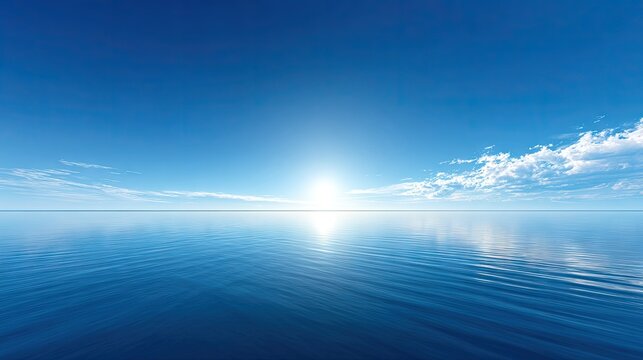 Brilliant sunlight illuminates a vast expanse of calm, deep blue water under a clear sky.