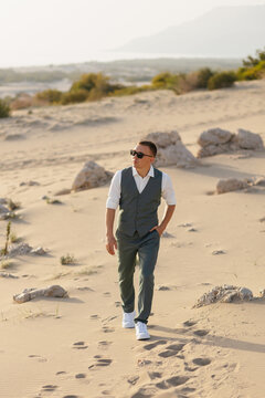 Stylish groom walking desert wearing suit waistcoat