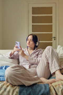 Portrait of a young non-binary person checking their phone at home