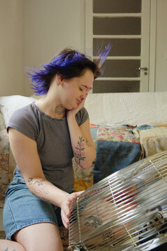 Alternative person looking uncomfortable by the heat in front of a fan