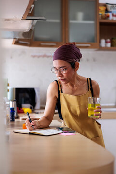 Writer writing in notebook in kitchen