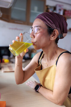 Woman in headscarf drinks liquid supplement