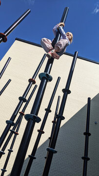 Young girl climbing a bamboo style climbing apparatus