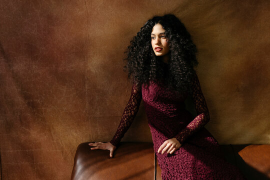 Woman with curly hair posing on sofa