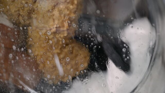 Stuffed animals washing inside laundry machine. Stuffed toys and plushies spinning in a washing machine with soapy water during a laundry cycle, seen from a close-up perspective through the glass door