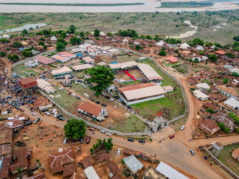 Aerial view of a large walled compound with a red carpet surrounded by traditional houses and the Niger River in the distance Idah, Kogi, Nigeria.