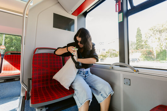 Woman Sitting on a Bus Looking Inside Her Bag in the Afternoon