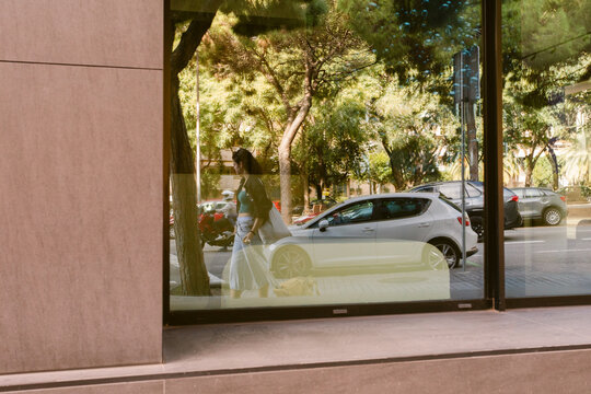 Woman Walking Past a Glass Window in a City Street Setting