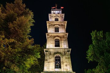 Obraz premium Historic Bursa clock tower illuminated at night with turkish flags