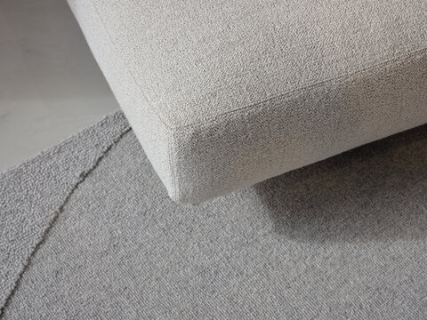 Detail of light couch
 grey rug and floor