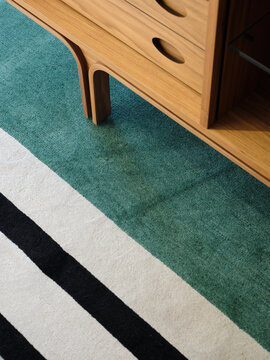 Detail of stylish sideboard with colourful stripped rug