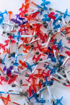 Colorful Medical Syringes Scattered on White Background