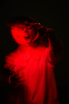 Person in dark space with red light and an open mouth