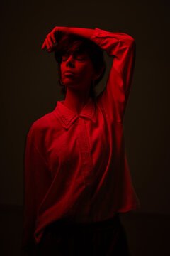 Woman poses with hand on head in red light in a studio setting