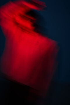 Person moving quickly with red lights in dark setting