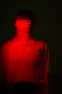 Movement in red light creates a blurred figure in a dark room