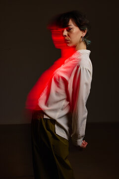 Model poses with red light in dark studio setting at night