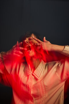 Woman expressing emotion with red light in dark room