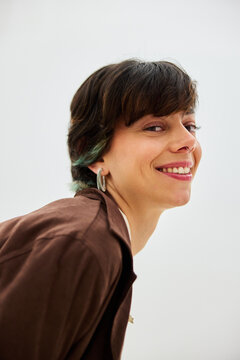 A woman with short dark hair smiles while looking back at the ca