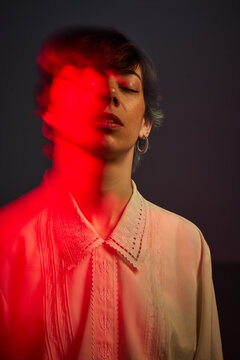 Woman standing with red light in a dark space at night