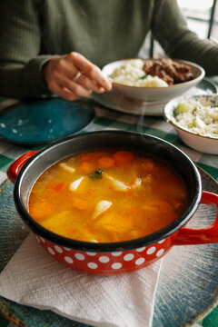 Hot Soup Served in a Red Bowl With Polka Dots on a Table