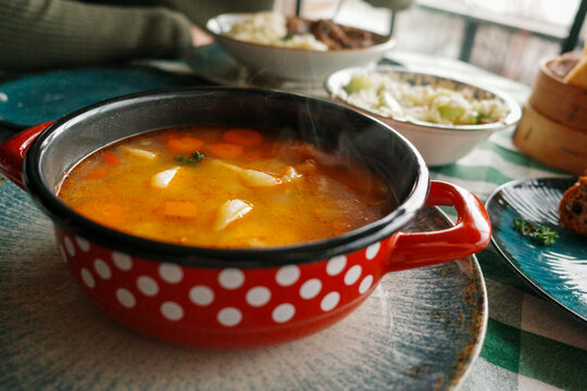 Hot Soup Served in a Red Bowl With Polka Dots on a Table