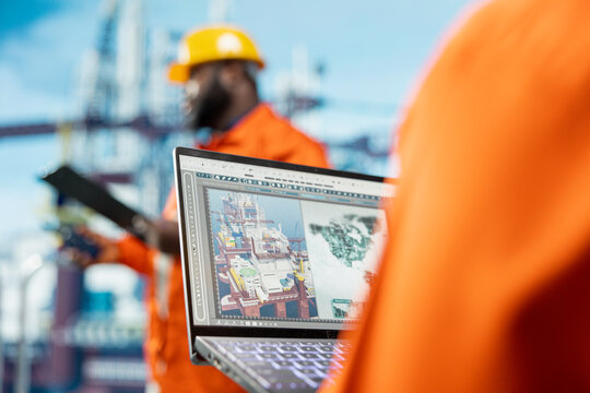 Close up of geophysicist analyzing map on device screen to determine best offshore drilling location. Specialist looking at global exploration data on notebook, selecting new well installation sites