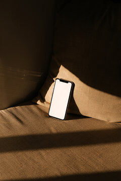 Phone With White Screen Rests on a Couch in a Warm Afternoon Light