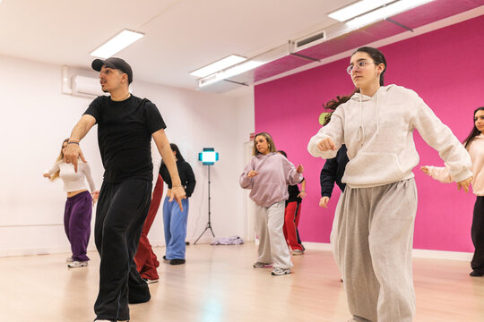 Male instructor teaching urban dance to teenagers in studio