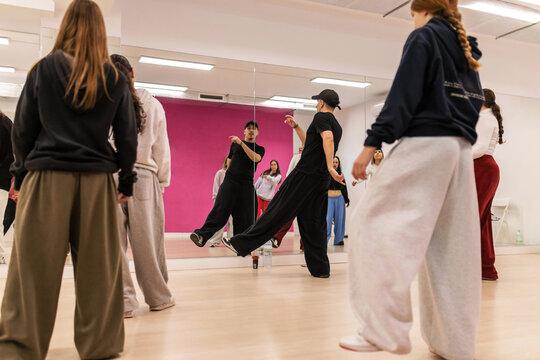 Male instructor teaching urban dance to teenagers in studio
