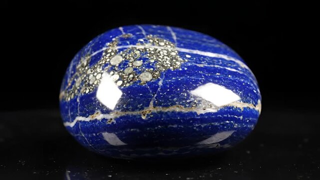 Polished Lapis Lazuli Gemstone with Pyrite Inclusions on Black Background.