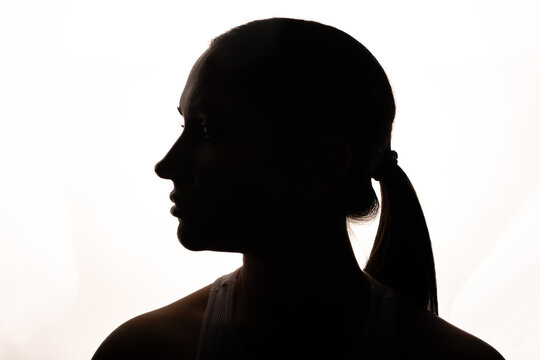 Backlit silhouette of woman standing in front of softbox in dark studio