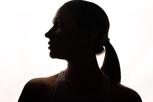 Backlit silhouette of woman standing in front of softbox in dark studio