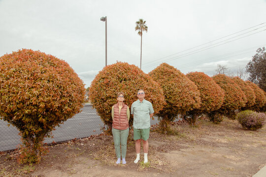 Solemn couple in front of hedges