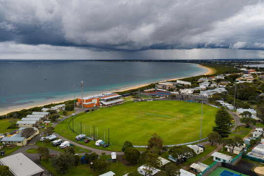 Rain falling from dark storm clouds advancing over a coast sports oval