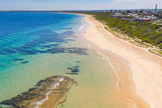 A long sandy beach and rocky reefs stretching to the horizon