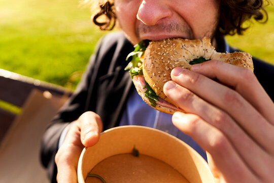 Man eating bagel outdoor, enjoying lunch in park