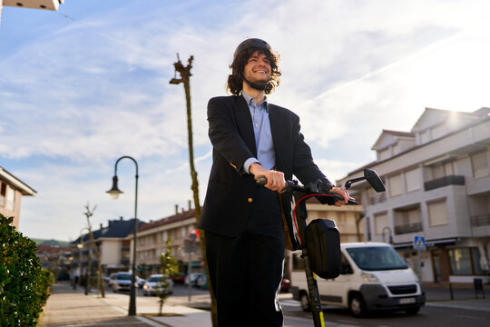 Smiling man riding electric scooter in city