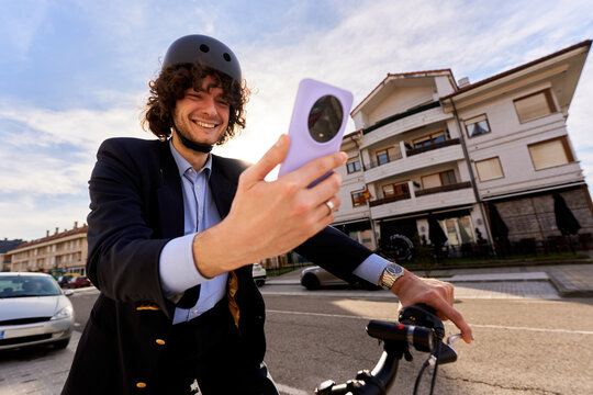 Businessman cycling urban street using smartphone for communication
