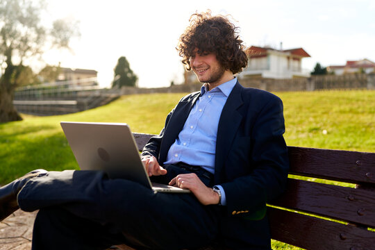 Young man remote working with laptop outdoors