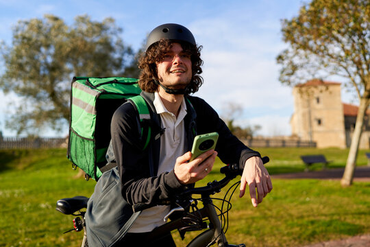 Delivery rider on bicycle checking smartphone app